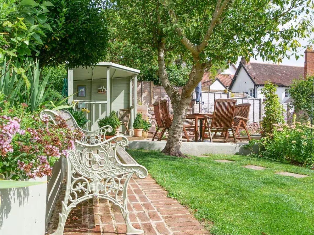 The cottage-style garden has a table and chairs for al fresco dining.