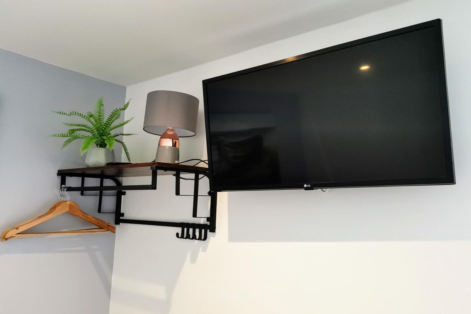 Smart TV, lamp, shelf with hangers underneath for clothes